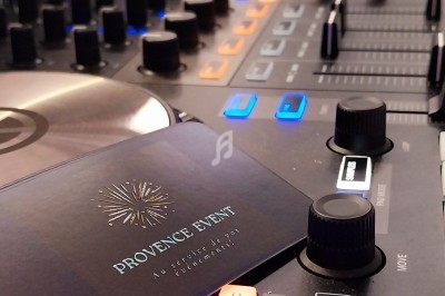 Table de mixage avec des boutons lumineux et une carte de visite posée dessus, dans un environnement intérieur.