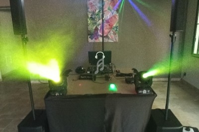 Installation de DJ avec table de mixage, haut-parleurs, jeux de lumières colorées et fumée dans une salle intérieure.
