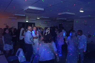 Groupe de personnes dans une salle sombre éclairée par des lumières colorées lors d'une fête ou d'un événement.