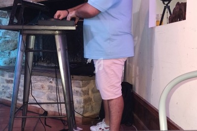 Un homme portant un casque audio mixe de la musique sur un clavier électronique dans une pièce décorée.