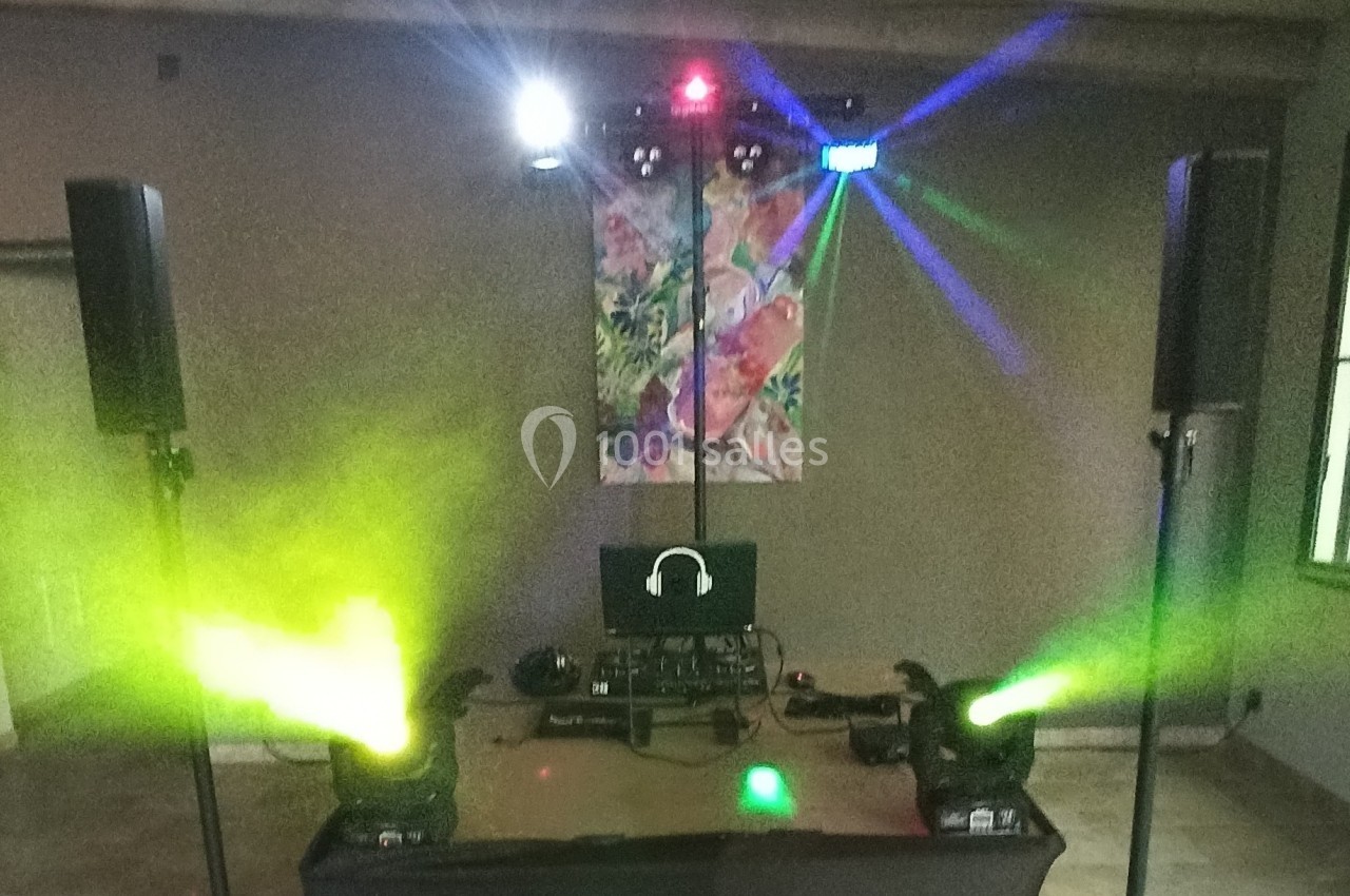 Équipement de sonorisation et éclairage avec projecteurs colorés, enceintes et ordinateur dans une salle.