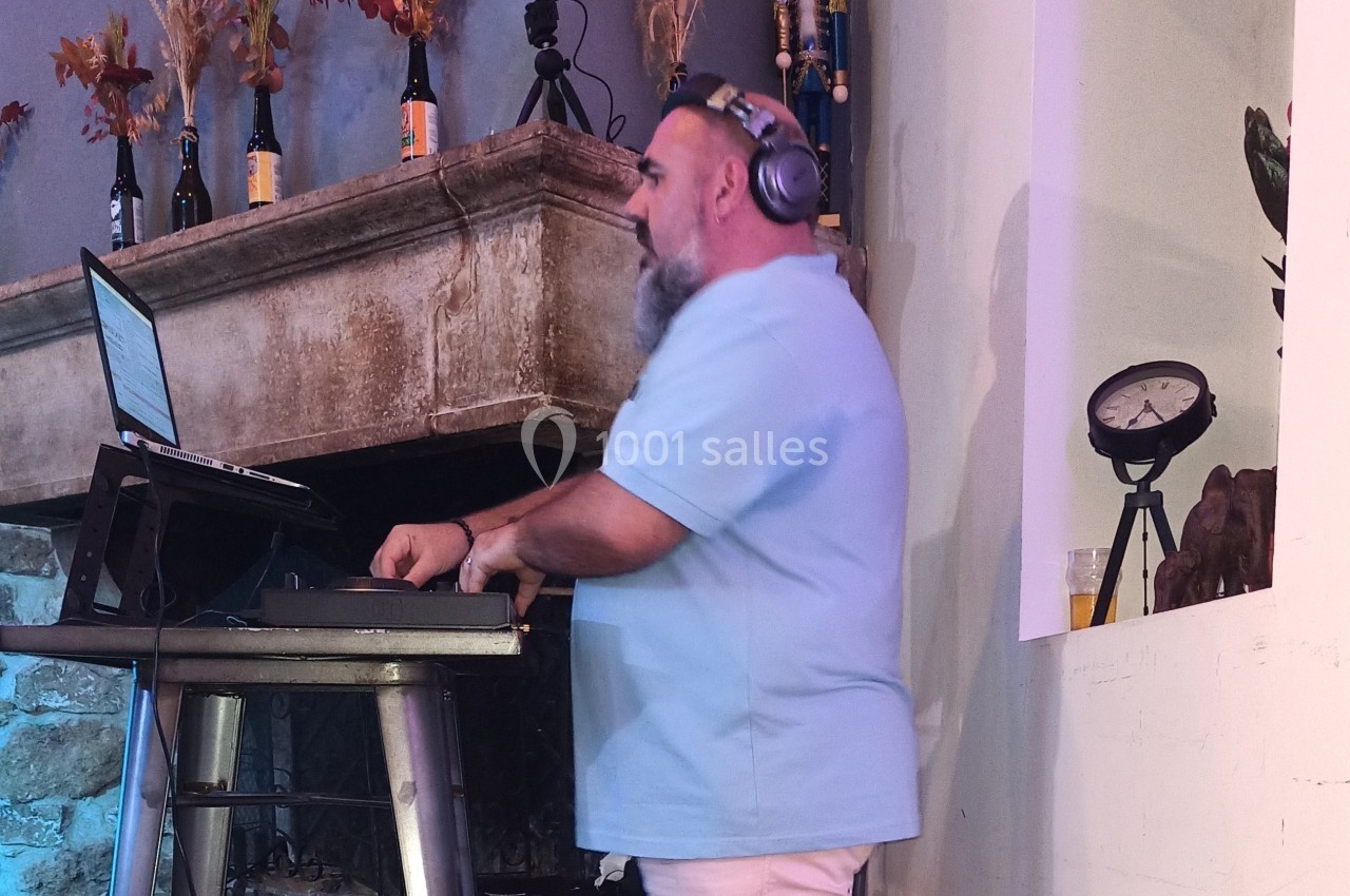 Un DJ portant un casque audio mixe de la musique sur une table équipée d'un ordinateur portable.