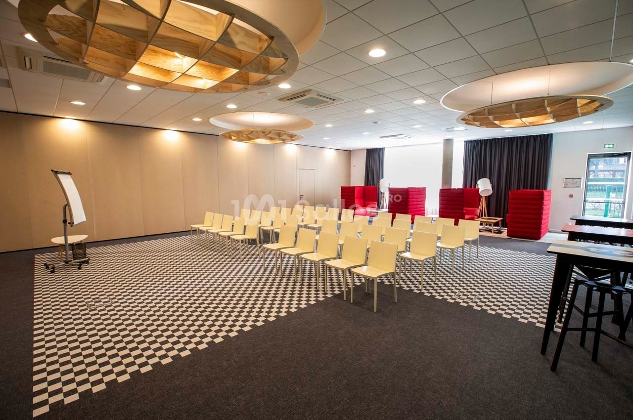 Salle de réunion avec chaises alignées face à un tableau blanc, éclairée par des plafonniers modernes.