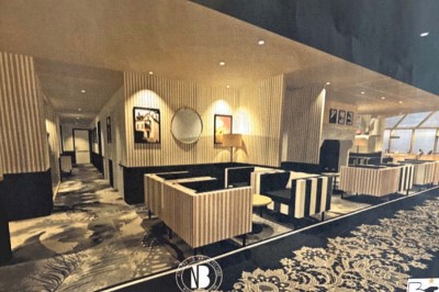 Façade d'un bâtiment clair avec terrasse, escalier en pierre et mobilier extérieur sous un ciel dégagé.