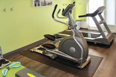 Façade d'un bâtiment clair avec terrasse, escalier en pierre et mobilier extérieur sous un ciel dégagé.
