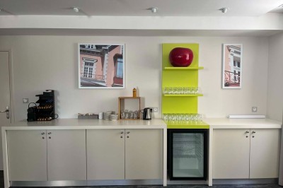 Façade d'un bâtiment clair avec terrasse, escalier en pierre et mobilier extérieur sous un ciel dégagé.