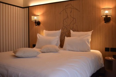 Façade d'un bâtiment clair avec terrasse, escalier en pierre et mobilier extérieur sous un ciel dégagé.