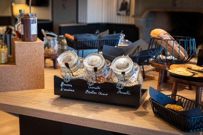 Bureau en bois clair avec une chaise, une machine à café, des tasses et une lampe murale allumée dans une chambre.