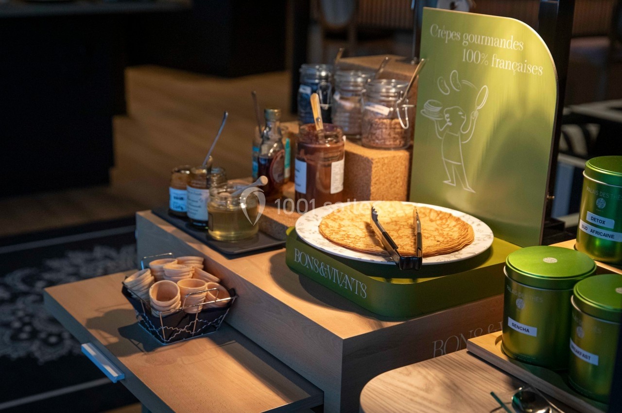 Crêpes présentées sur un comptoir avec pots de garnitures, miel et accessoires pour le service.