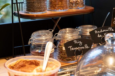 Bureau en bois clair avec une chaise, une machine à café, des tasses et une lampe murale allumée dans une chambre.