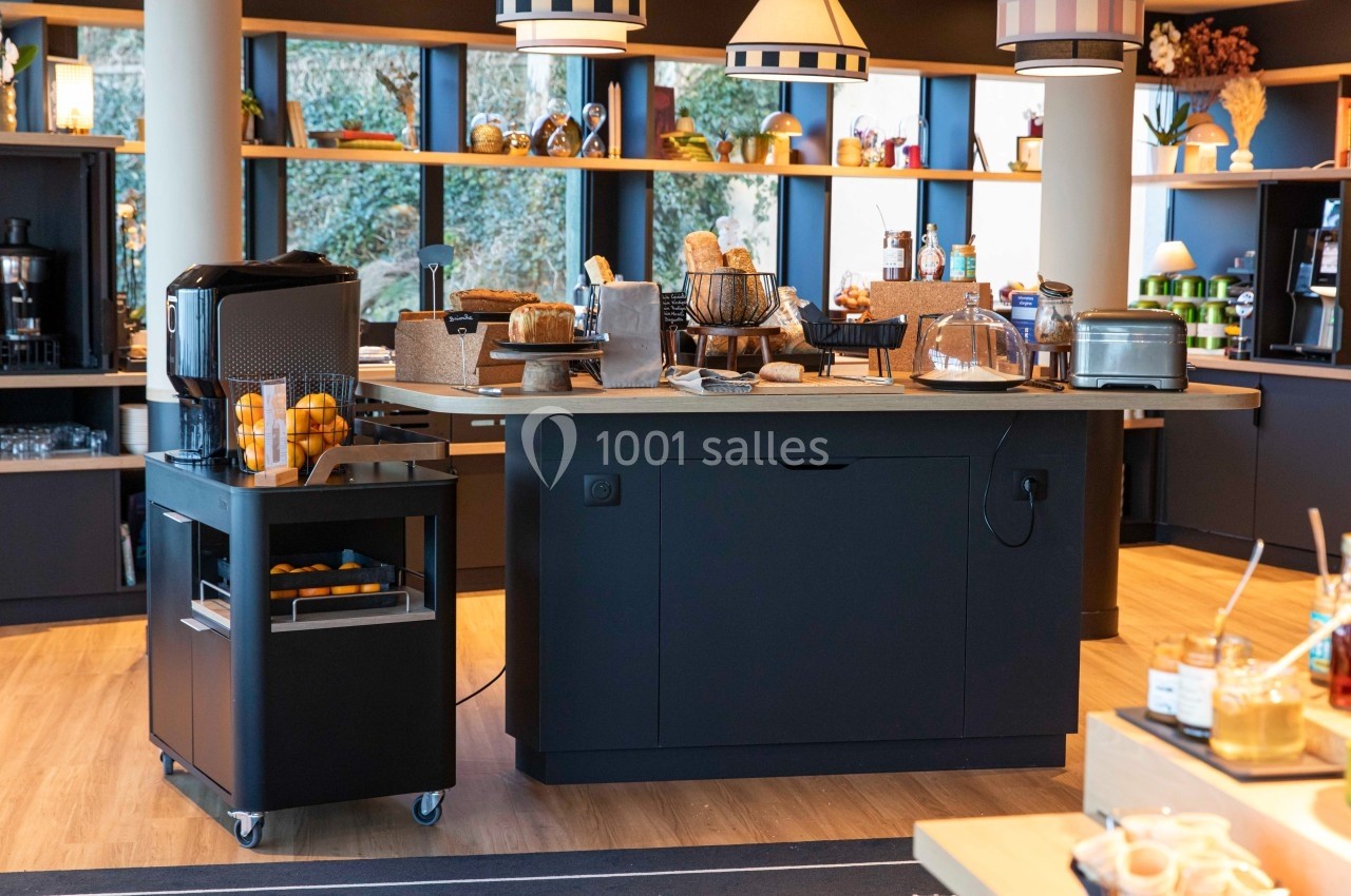 Buffet de petit-déjeuner avec grille-pain, viennoiseries, jus d'orange et équipements de cuisine sur un comptoir moderne.