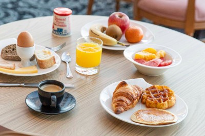 Bureau en bois clair avec une chaise, une machine à café, des tasses et une lampe murale allumée dans une chambre.