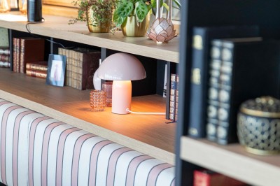 Bureau en bois clair avec une chaise, une machine à café, des tasses et une lampe murale allumée dans une chambre.