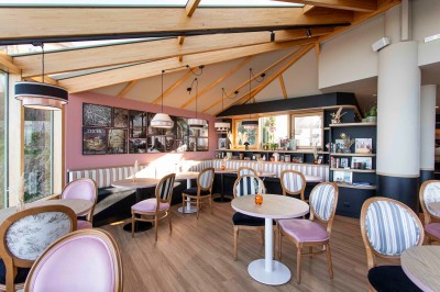 Bureau en bois clair avec une chaise, une machine à café, des tasses et une lampe murale allumée dans une chambre.
