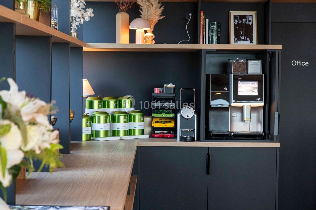 Coin café moderne avec machine à café automatique, capsules colorées et étagères en bois dans un espace bureau.