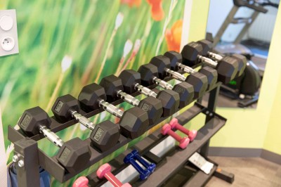 Bureau en bois clair avec une chaise, une machine à café, des tasses et une lampe murale allumée dans une chambre.