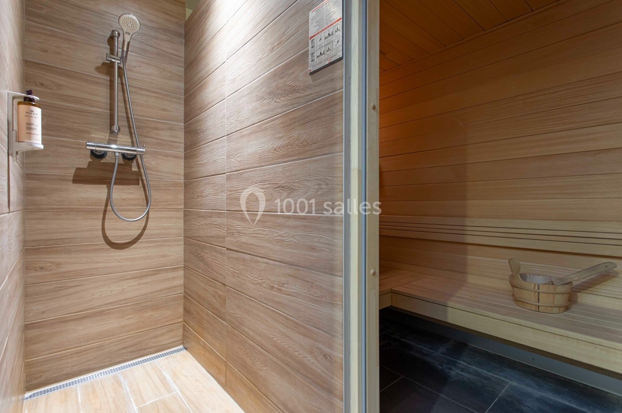 Douche moderne avec parois en bois à gauche et sauna en bois clair avec seau en bois à droite.