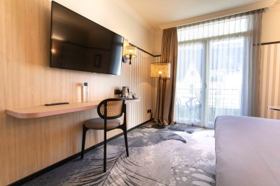 Bureau en bois clair avec une chaise, une machine à café, des tasses et une lampe murale allumée dans une chambre.