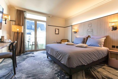 Bureau en bois clair avec une chaise, une machine à café, des tasses et une lampe murale allumée dans une chambre.