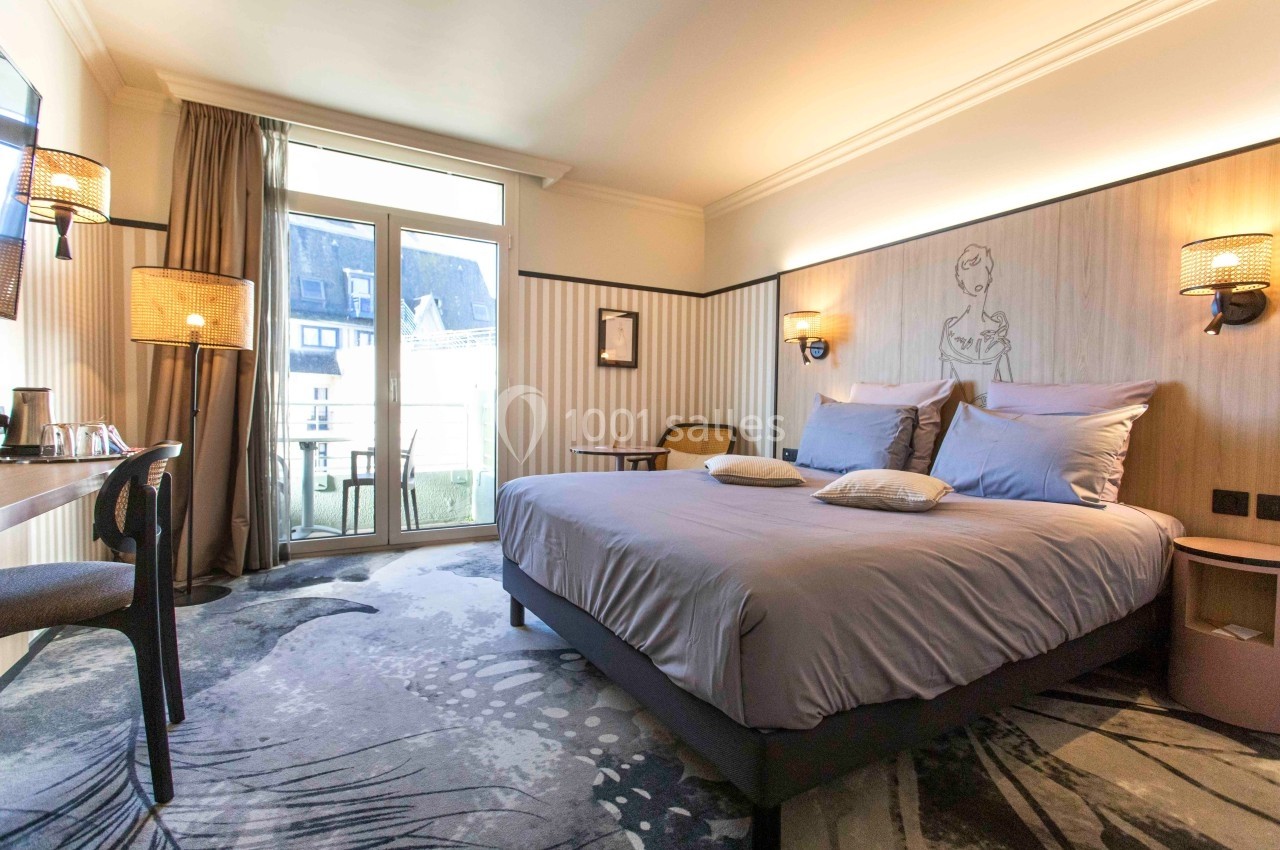 Chambre d'hôtel lumineuse avec un grand lit, décoration moderne, bureau, et balcon donnant sur l'extérieur.