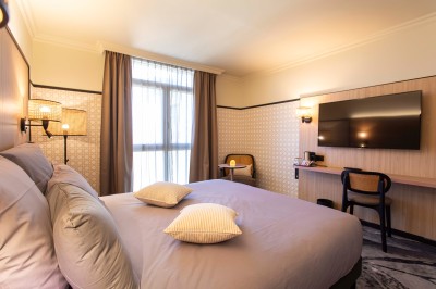 Bureau en bois clair avec une chaise, une machine à café, des tasses et une lampe murale allumée dans une chambre.