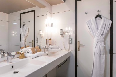 Bureau en bois clair avec une chaise, une machine à café, des tasses et une lampe murale allumée dans une chambre.