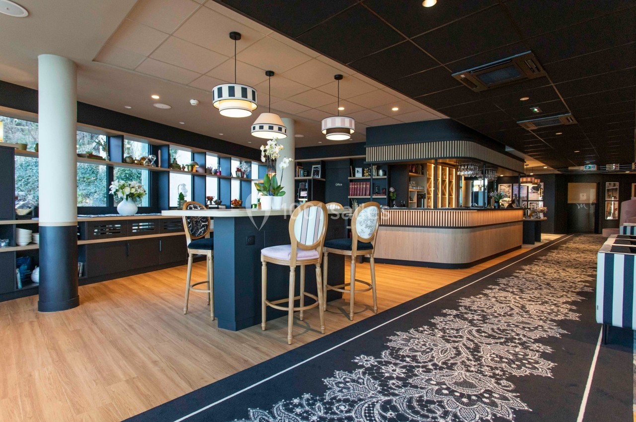 Intérieur d'un restaurant moderne avec comptoir, tables hautes, décor élégant et éclairage chaleureux.