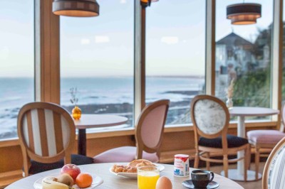 Bureau en bois clair avec une chaise, une machine à café, des tasses et une lampe murale allumée dans une chambre.