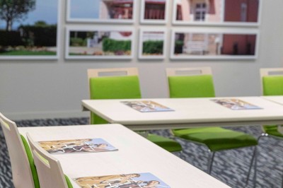Bureau en bois clair avec une chaise, une machine à café, des tasses et une lampe murale allumée dans une chambre.