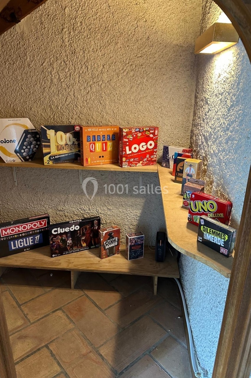 Étagères en bois dans un coin de pièce, présentant divers jeux de société colorés.