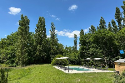 Escalier en bois avec rambarde, dans un intérieur aux murs blancs texturés et sol en carrelage.