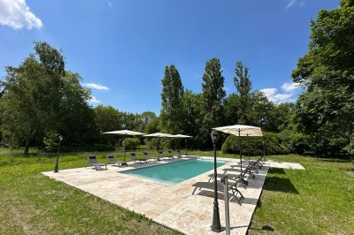 Escalier en bois avec rambarde, dans un intérieur aux murs blancs texturés et sol en carrelage.