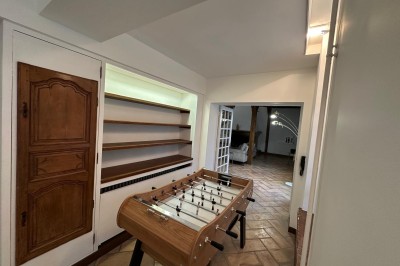 Escalier en bois avec rambarde, dans un intérieur aux murs blancs texturés et sol en carrelage.