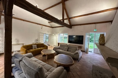 Escalier en bois avec rambarde, dans un intérieur aux murs blancs texturés et sol en carrelage.