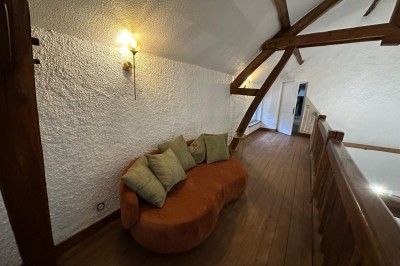 Escalier en bois avec rambarde, dans un intérieur aux murs blancs texturés et sol en carrelage.