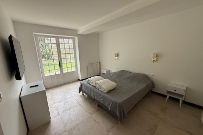 Escalier en bois avec rambarde, dans un intérieur aux murs blancs texturés et sol en carrelage.