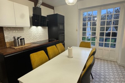 Escalier en bois avec rambarde, dans un intérieur aux murs blancs texturés et sol en carrelage.