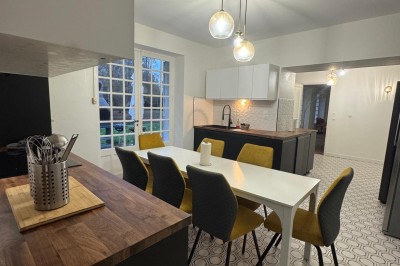 Escalier en bois avec rambarde, dans un intérieur aux murs blancs texturés et sol en carrelage.