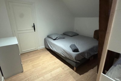 Escalier en bois avec rambarde, dans un intérieur aux murs blancs texturés et sol en carrelage.