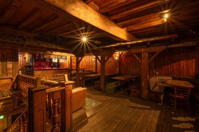 Miniature Salle du Haut Salle en bois chaleureux avec un baby-foot au centre, entourée de tables et chaises, éclairage tamisé.