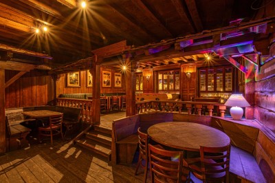 Miniature Salle du Haut Salle en bois chaleureux avec un baby-foot au centre, entourée de tables et chaises, éclairage tamisé.