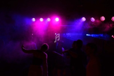 Un homme chante sur scène avec un micro, éclairé par une lumière rouge dans une ambiance sombre.