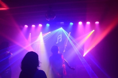 Un homme chante sur scène avec un micro, éclairé par une lumière rouge dans une ambiance sombre.