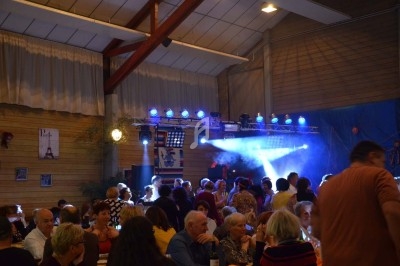 Un homme chante sur scène avec un micro, éclairé par une lumière rouge dans une ambiance sombre.