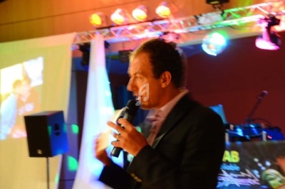 Un homme chante sur scène avec un micro, éclairé par une lumière rouge dans une ambiance sombre.