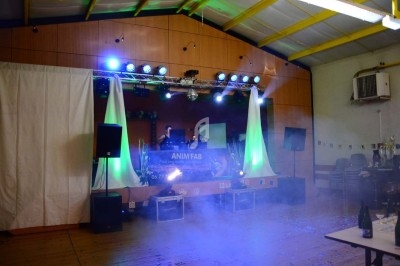 Un homme chante sur scène avec un micro, éclairé par une lumière rouge dans une ambiance sombre.