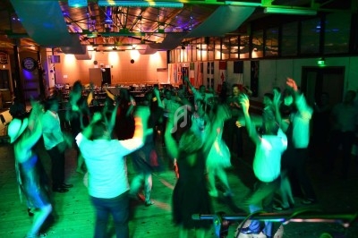 Un homme chante sur scène avec un micro, éclairé par une lumière rouge dans une ambiance sombre.