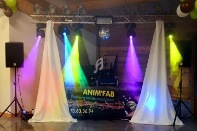 Un homme chante sur scène avec un micro, éclairé par une lumière rouge dans une ambiance sombre.