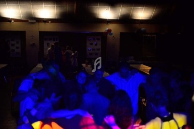 Groupe de personnes dans une salle faiblement éclairée, éclairée par des lumières colorées lors d'un événement festif.