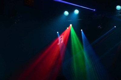 Éclairage de scène avec faisceaux lumineux rouge, vert et bleu sous des projecteurs dans une ambiance sombre.